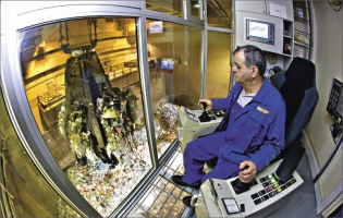 Operátor ze zásobníku překládá odpad drapákem na stupňový rošt spalovací komory