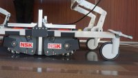 Prototyp motorizovaného asistenčního robotu NSK instalovaný na základně nosítek